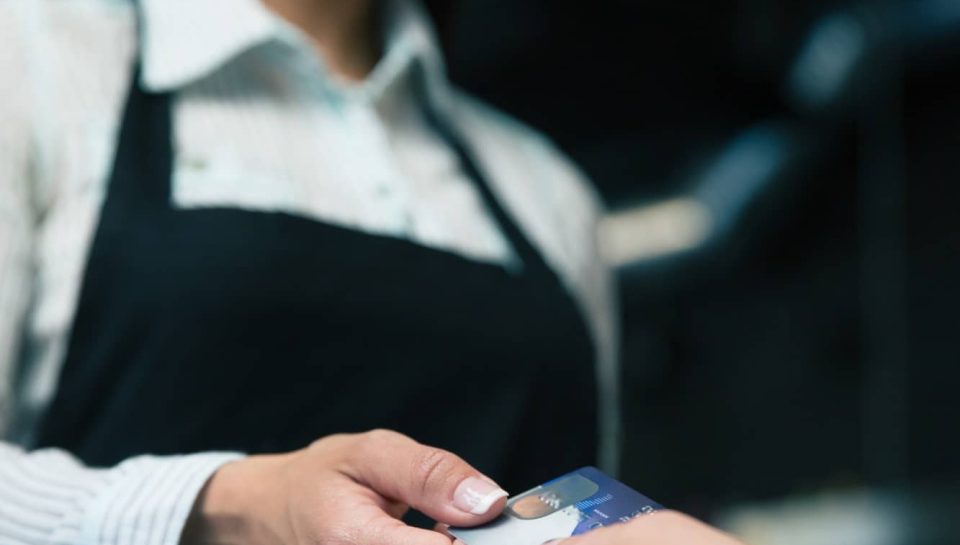 Man giving bank card to female waiter in cafe. Focus on card
